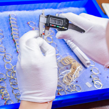 Gloved hands holding calipers to measure jewelry