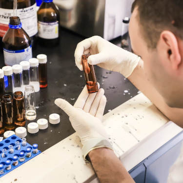 Man examining a vial of fluid during a lab test