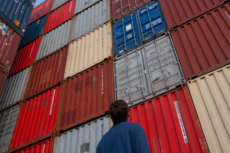 Man looking up at shipping containers