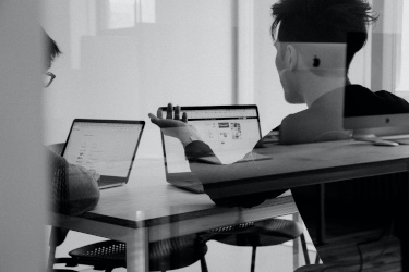 Men discussing business while sitting at table with laptops