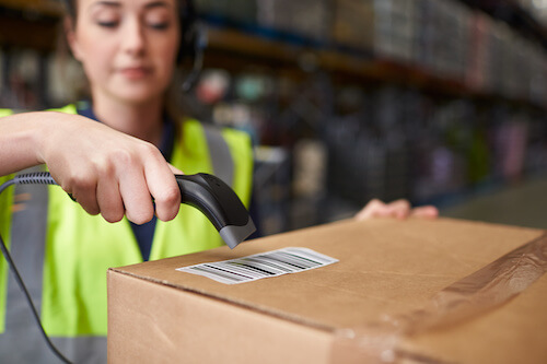 Woman using barcode reader on a box in a warehouse