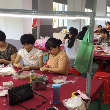 A group of women sitting at a table and working in a factory