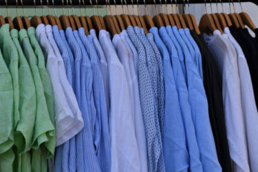 Blue and green shirts hanging on a rack