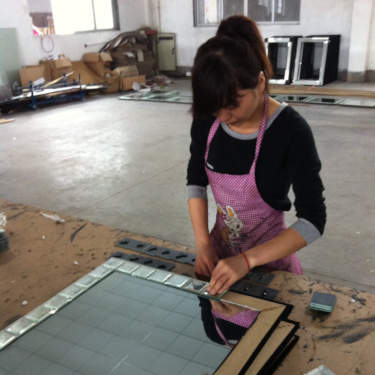 Woman assembling mirror at a factory