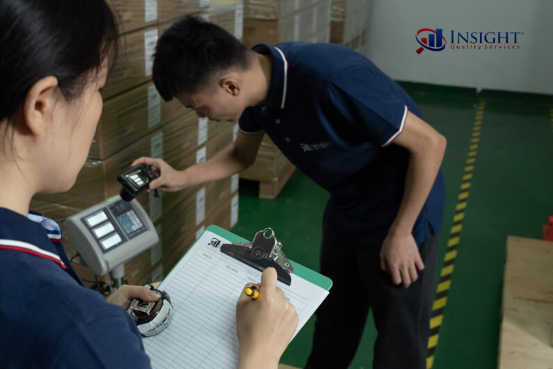 Two inspectors weighing cartons and holding a checklist