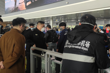Crowd of people wearing masks at Changchun Longjia Airport security checkpoint