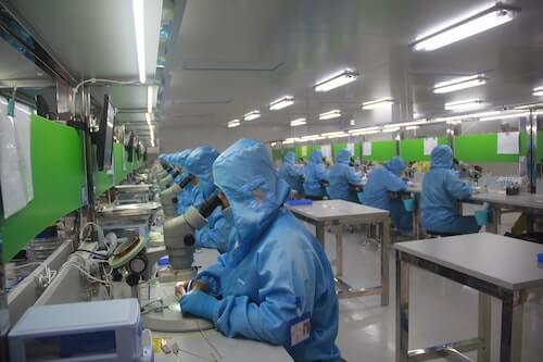 Workers looking into microscopes in an electronics factory