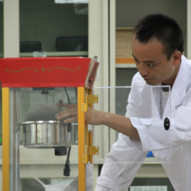Man in lab coat examining a popcorn machine