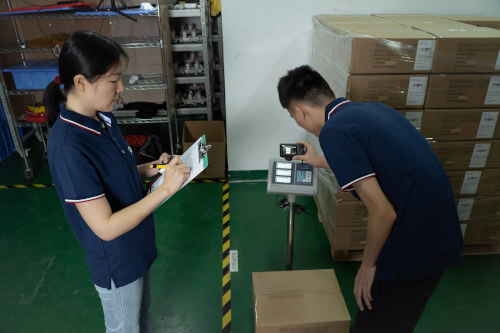 Inspectors verifying carton weight and recording it on a quality control checklist