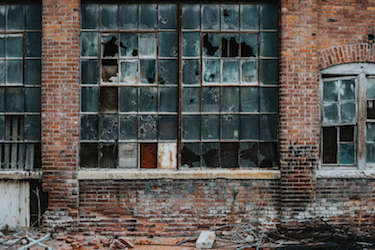 The outside of an abandoned warehouse with broken windows