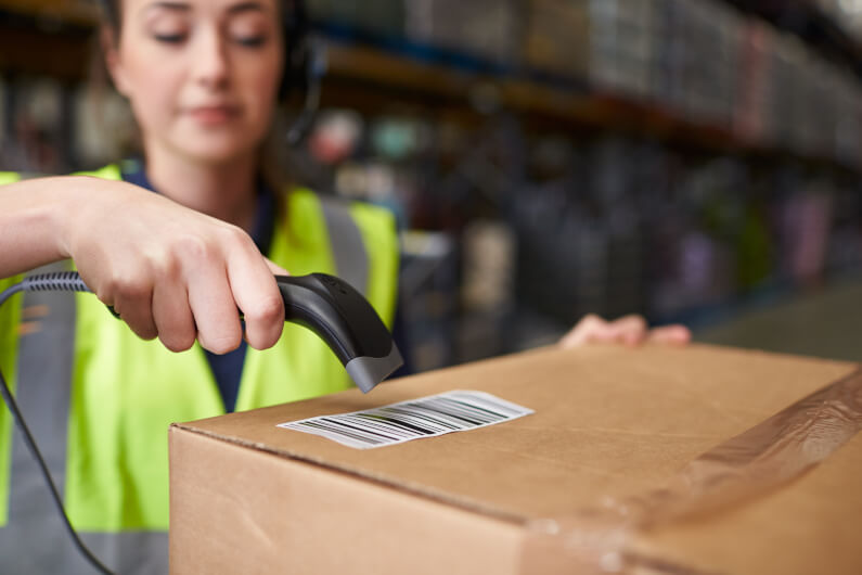 Woman using barcode reader on a box in a warehouse, detail