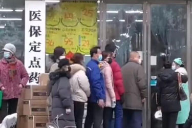 Citizens of Wuhan line up outside a drugstore wearing surgical masks