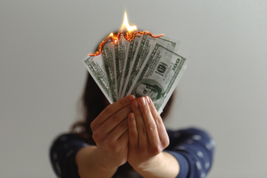 Young woman holding burning cash